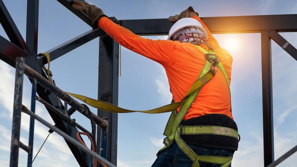 Construction worker using fall protection harness while working at height on a scaffold platform